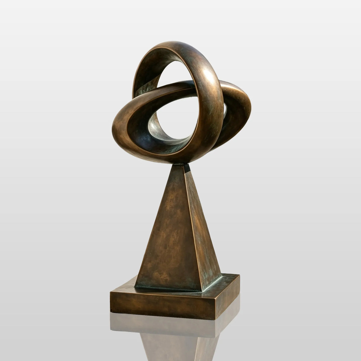 This bronze loop sculpture stands on paved walkway outside a modern house.