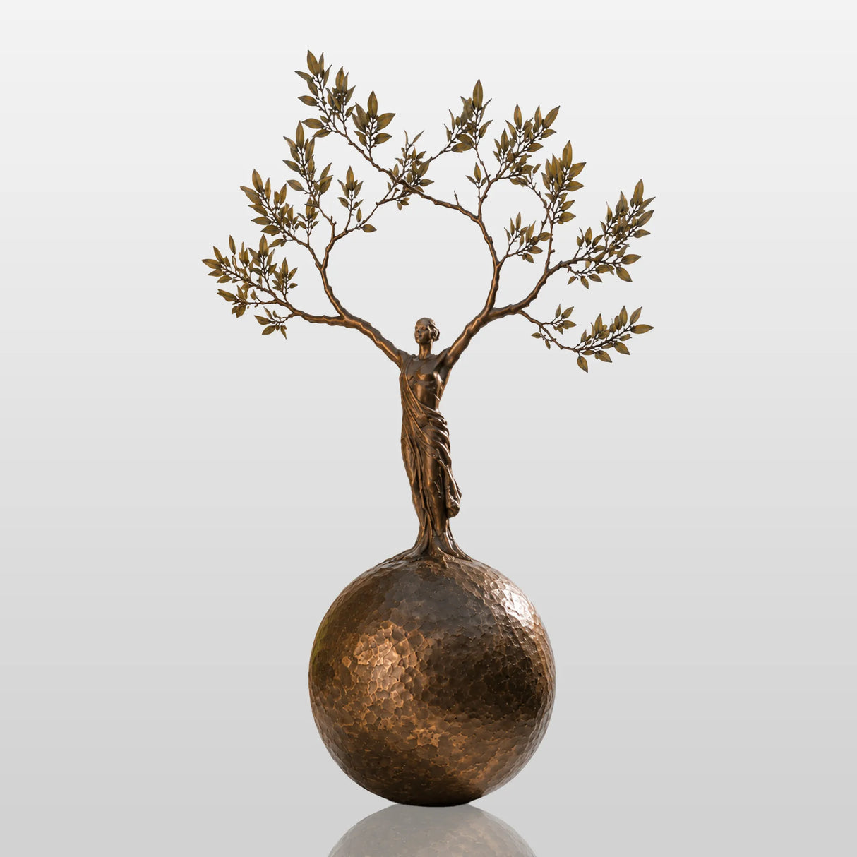 Bronze sculpture with the design of human shaped tree ball stands in a cobblestone courtyard.