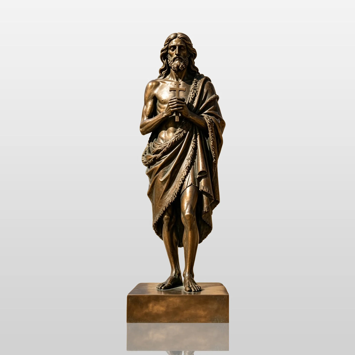A bronze St. John the Baptist statue stands in a sunlit church courtyard.