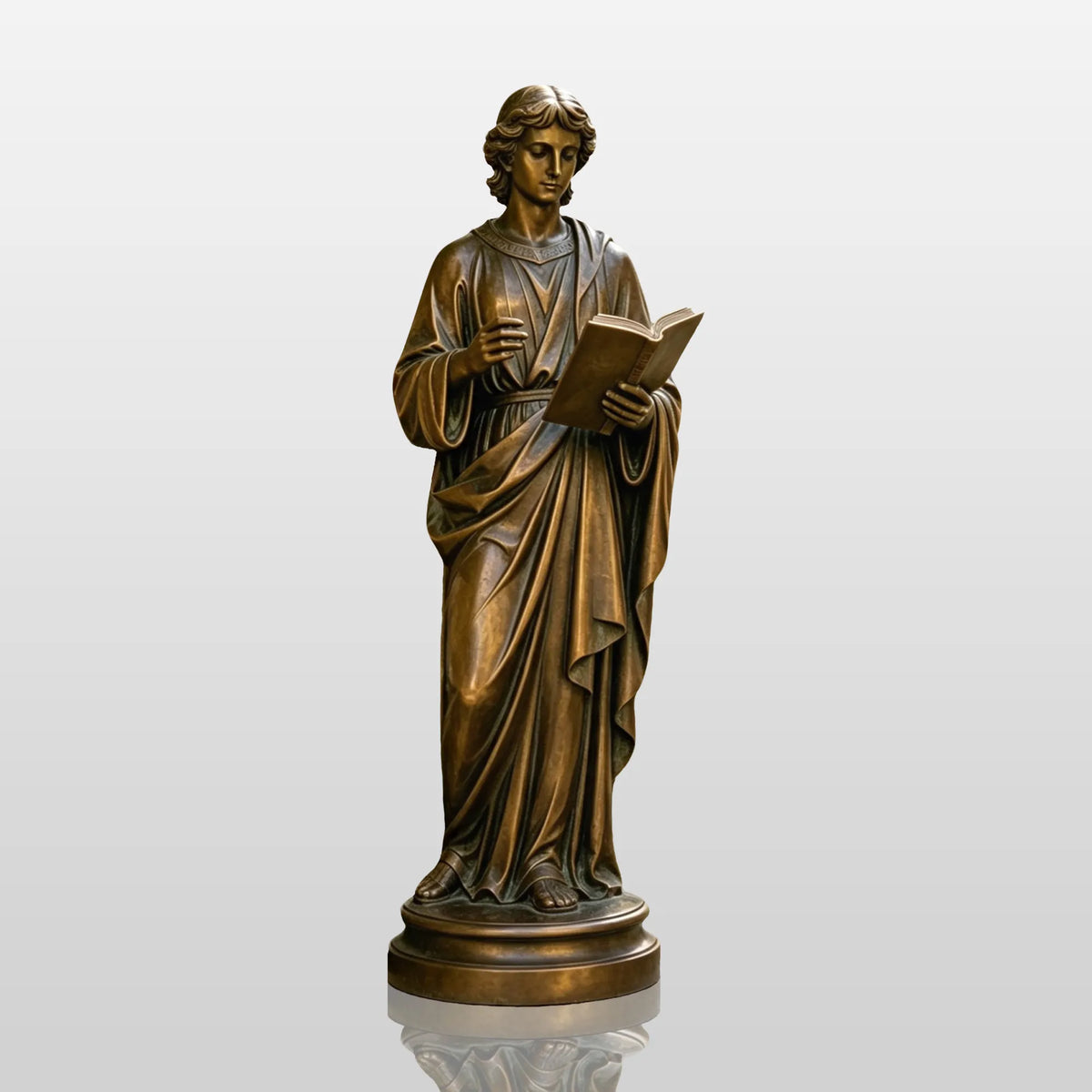A bronze St. John the Apostle statue stands on stone paving in a sunlit courtyard garden.