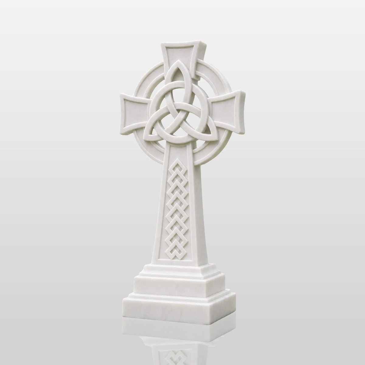 White marble Celtic cross headstone rests on gravel ground surrounded.