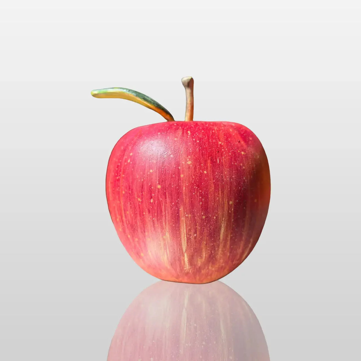 Fiberglass red apple sculpture is displayed on the dark marble table indoors.
