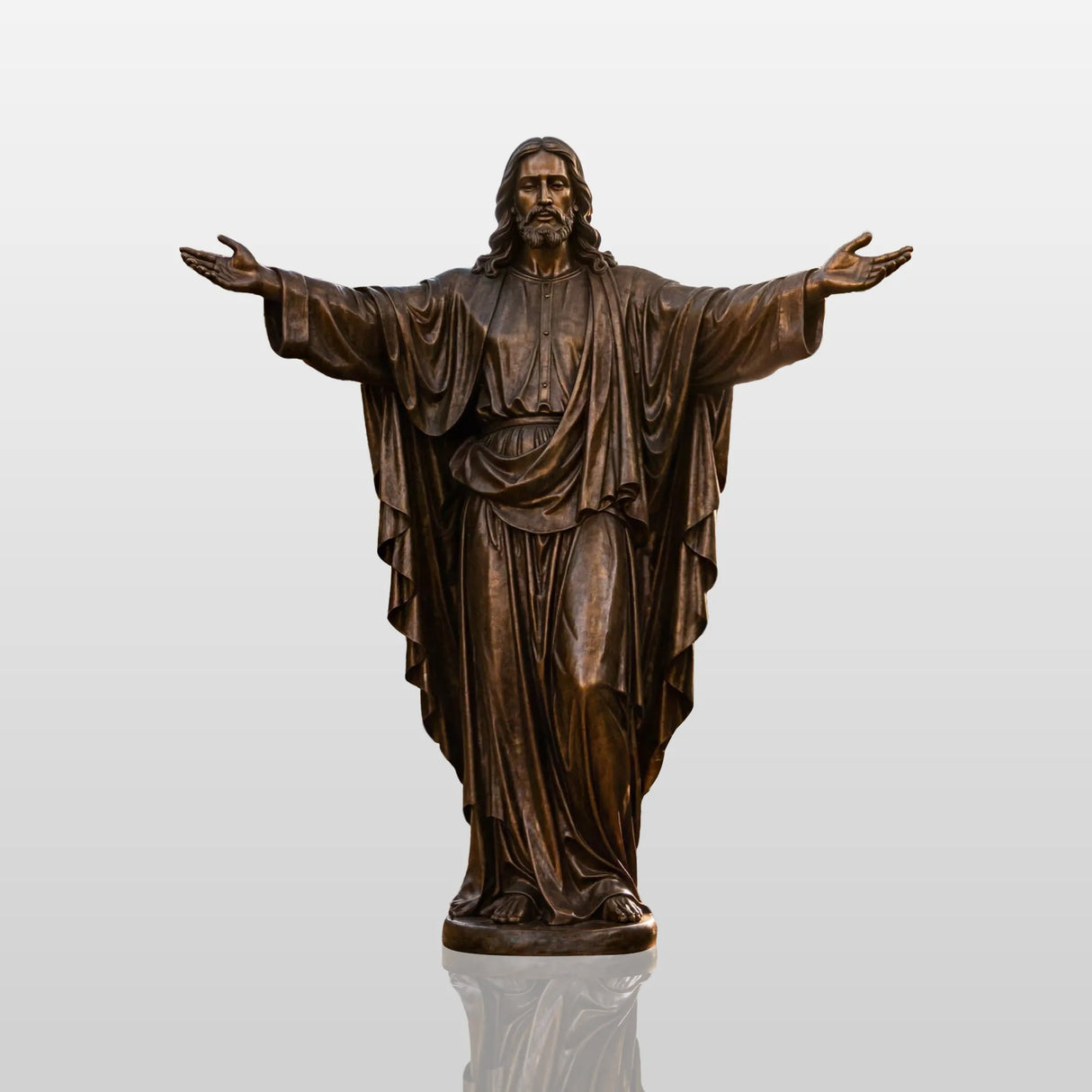 Bronze Jesus statue with open arms stands stands on a base along a church garden walkway.