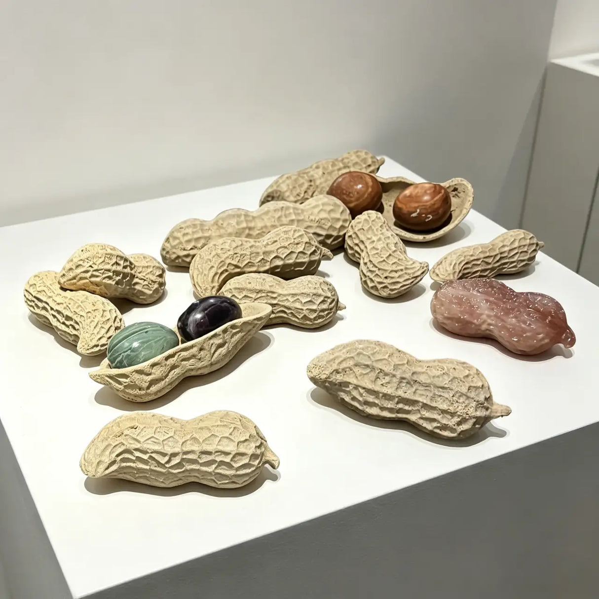 A group of abstract marble sculptures shaped like peanuts is displayed on a white pedestal.