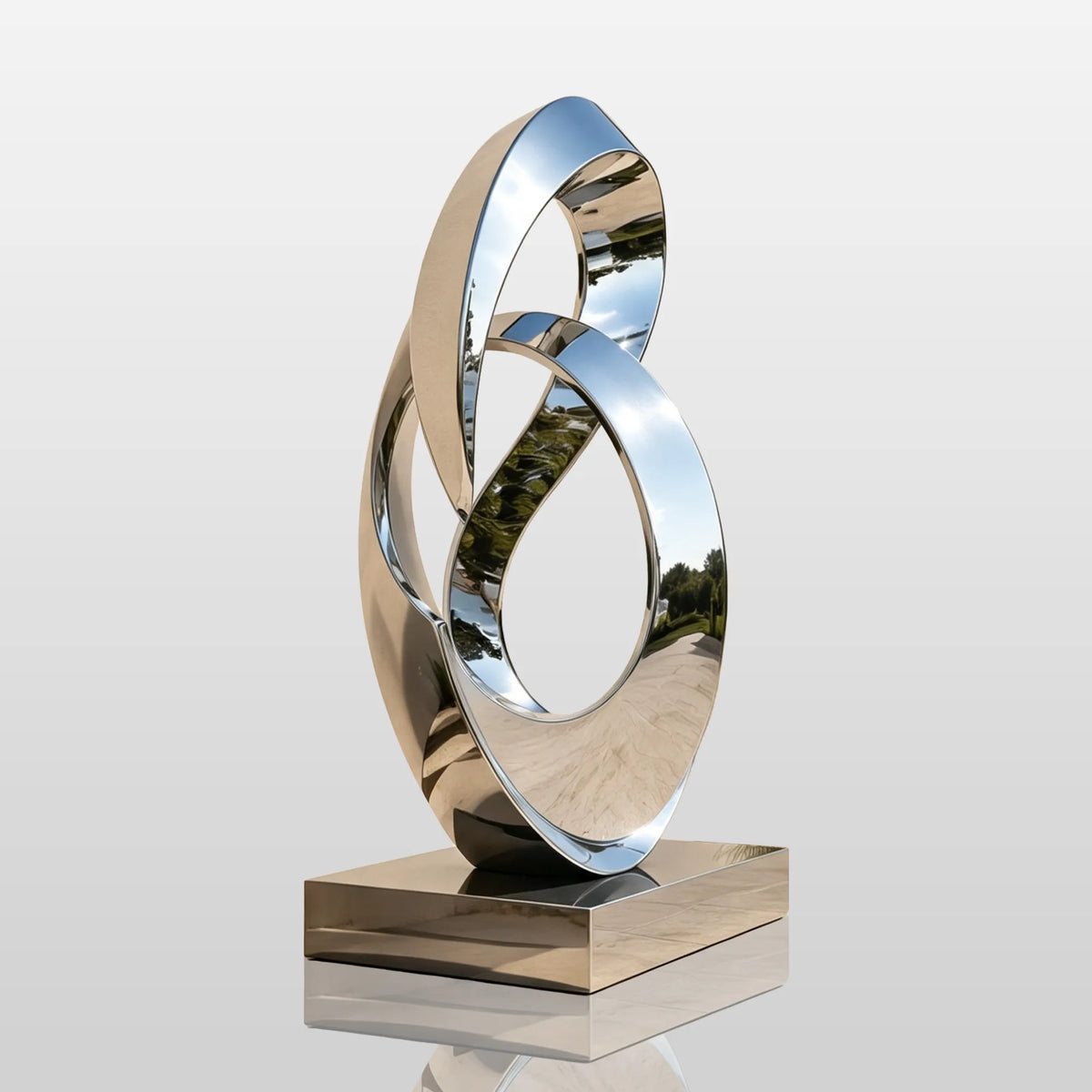A stainless steel intertwined loop sculpture stands beside a walkway in front of a building.