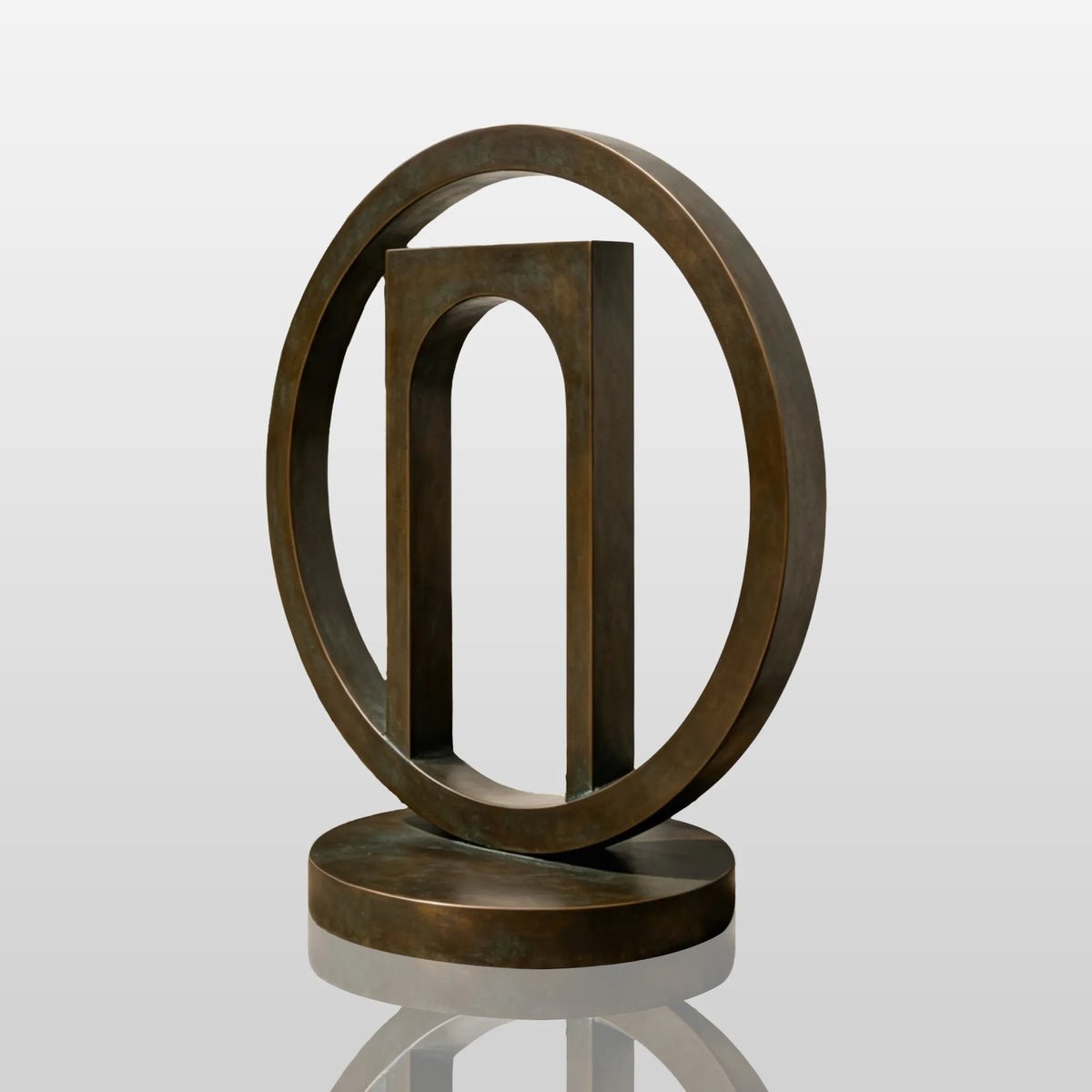The geometric bronze sculpture stands in gravel planting bed near a home entrance.