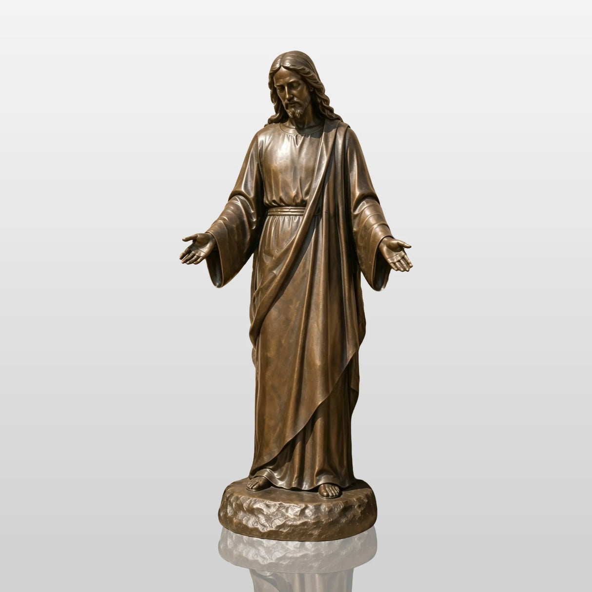 Bronze Jesus statue with open hands stands against stone wall surrounded by blooming roses.