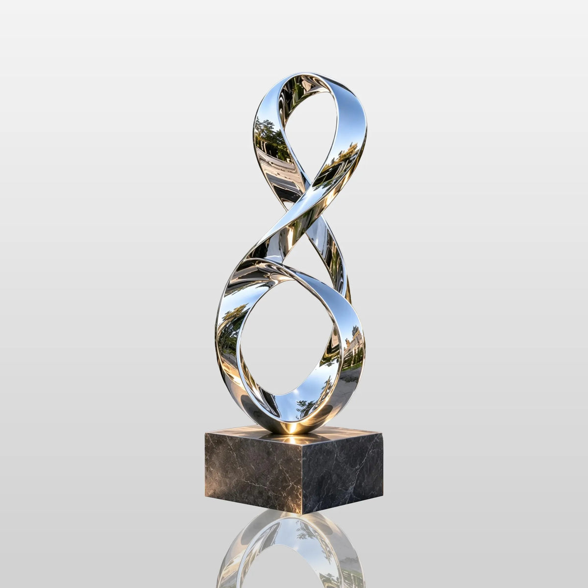 Polished stainless steel ribbon sculpture rests beside a garden water pond.