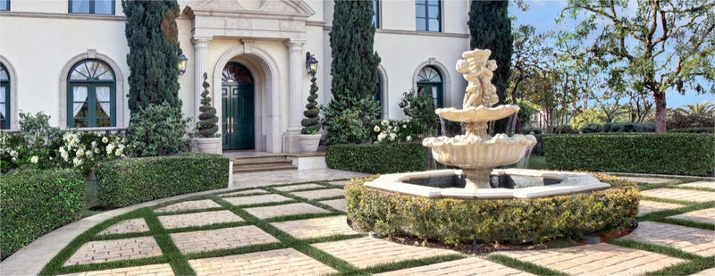 A beautiful two-tiered stone fountain features a statue of an angel