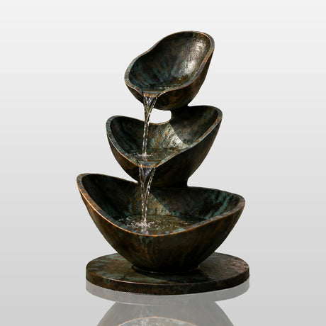 Three tier bronze fountain pours flowing water in an outdoor garden.