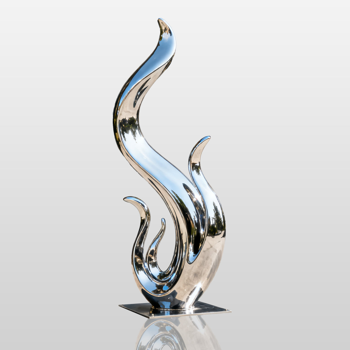 Abstract stainless steel flame sculpture with fluid wave like curves and a polished mirror finish displayed in a modern villa garden.