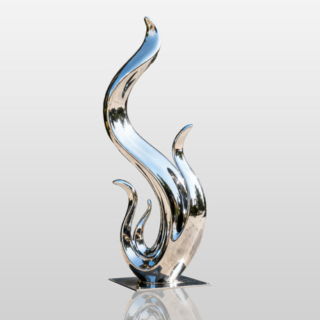 Abstract stainless steel flame sculpture with fluid wave like curves and a polished mirror finish displayed in a modern villa garden.