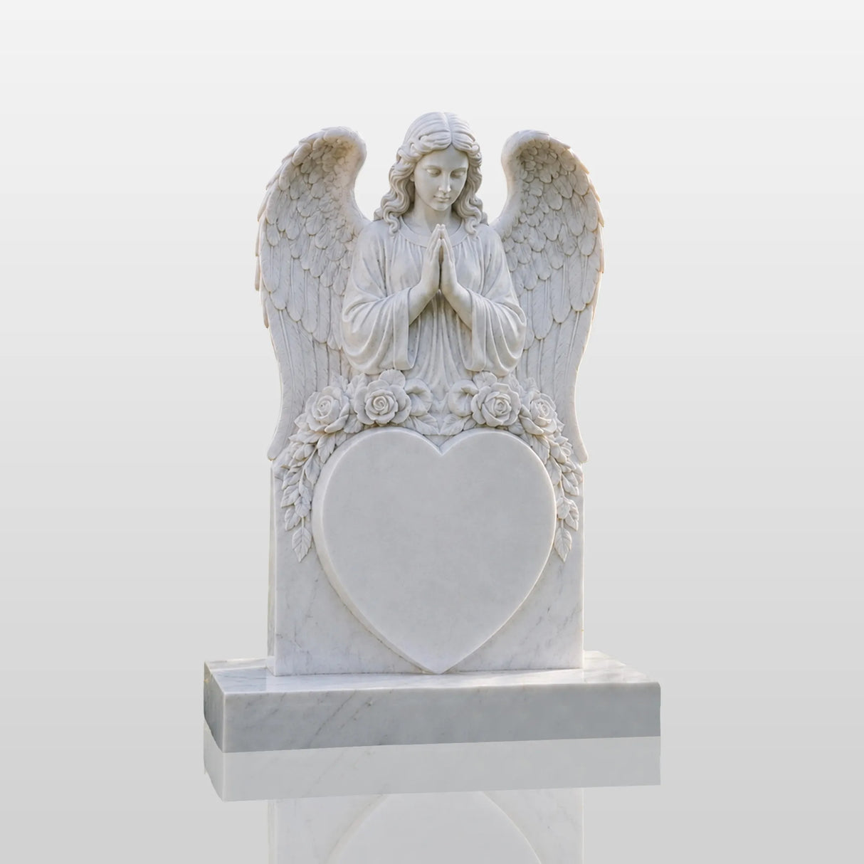 Marble tombstone carved with praying angel, roses and heart stands on the lush green cemetery lawn.