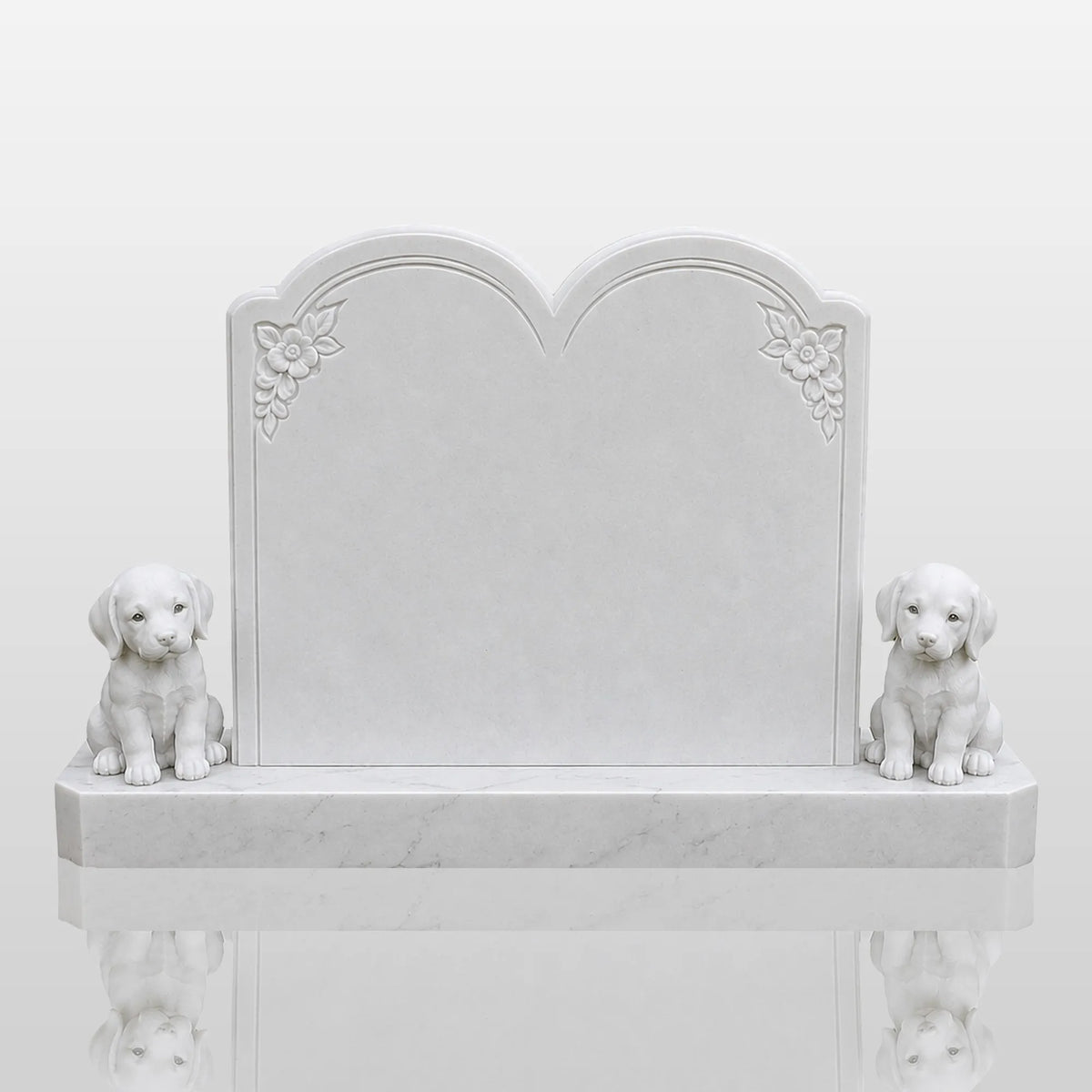 A white marble tombstone with two puppy statues stands on green grass inside a cemetery.