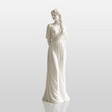 A white marble female statue stands gracefully in an elegant classical interior with warm curved details.