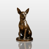 Bronze chihuahua dog statue sits on wooden entryway ledge inside home.