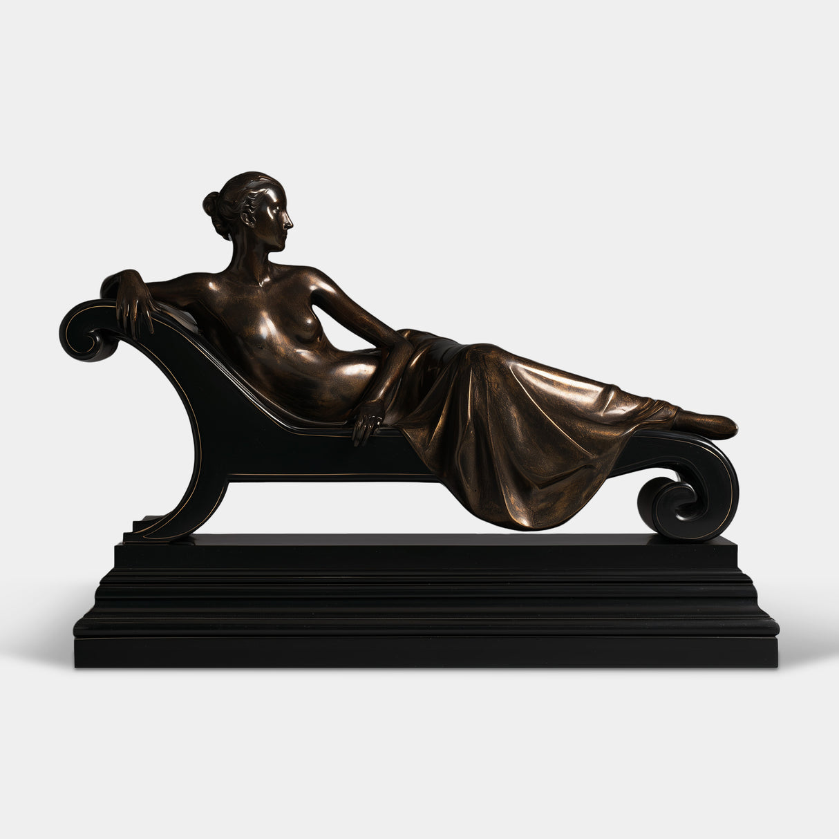 Bronze tabletop sculpture presents a semi nude lady, reclining on studded scroll chaise lounge with multi layer black base.