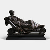 Bronze tabletop sculpture shows a draped female reclining on scroll chaise lounge.