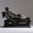 Bronze tabletop sculpture shows a draped female reclining on scroll chaise lounge.