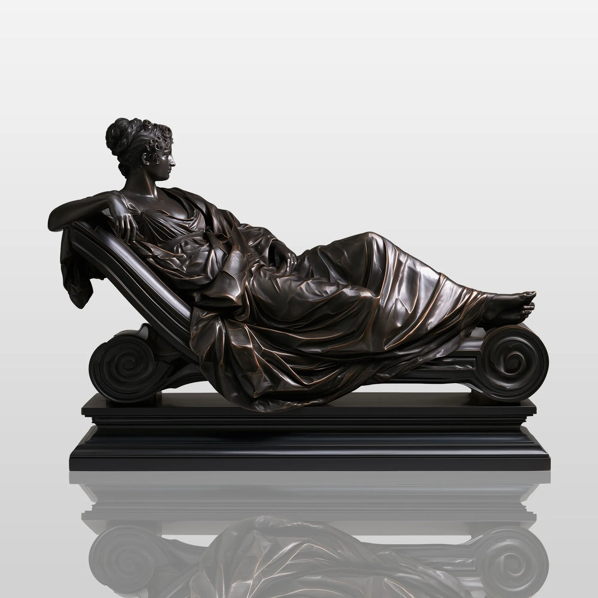 Bronze reclining lady sculpture rests on marble mantel inside elegant classic room.