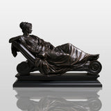 Bronze reclining lady sculpture rests on marble mantel inside elegant classic room.