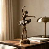 Bronze ballerina table sculpture stands on the wooden desk under soft indoor sunlight.