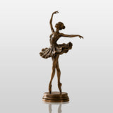 Bronze ballerina table sculpture stands on the wooden desk under soft indoor sunlight.