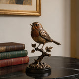Bronze robin bird table sculpture sits on the black marble table beside stacked hardcover books.