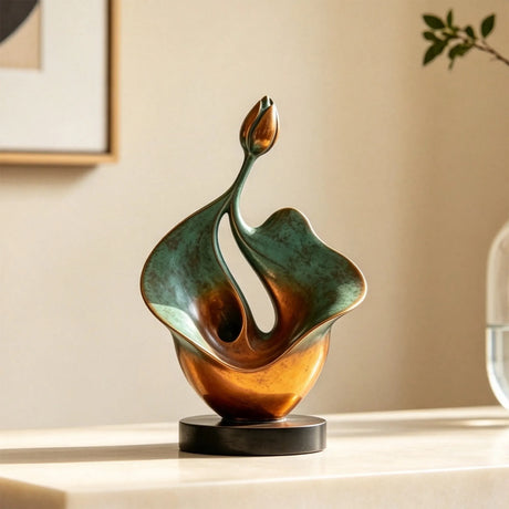 An abstract bronze lotus sculpture is set on a light table indoors.
