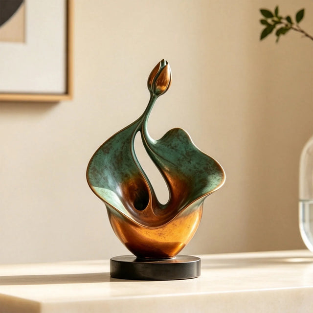 An abstract bronze lotus sculpture is set on a light table indoors.