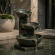 Three tier bronze bowl fountain sits outdoors with water flowing down each bowl.