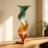 An abstract vase bronze sculpture stands on a wooden cabinet in a sunlit room.