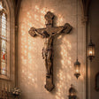 Religious bronze Jesus crucifix wall sculpture mounts on church wall beside vintage hanging lanterns and soft glass light.