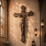 Religious bronze Jesus crucifix wall sculpture mounts on church wall beside vintage hanging lanterns and soft glass light.