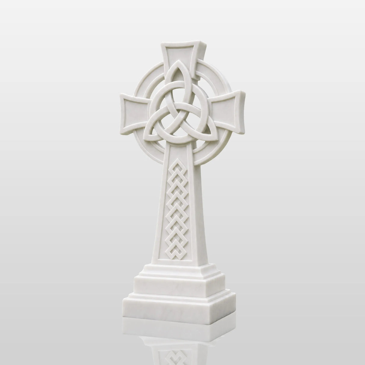 White marble Celtic cross headstone rests on gravel ground surrounded.