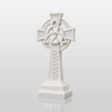 White marble Celtic cross headstone rests on gravel ground surrounded.