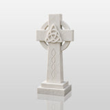The marble Celtic cross headstone sits on dark gravel among green garden shrubs.