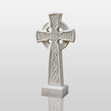 White Celtic cross marble headstone stands on grass beside a pathway.