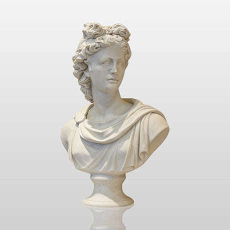 A white Greek Apollo marble bust sits on a carved marble console table before a gold framed mirror in a classic interior.