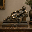 A bronze reclining lady sculpture rests on the marble tabletop.