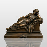 A bronze reclining lady sculpture rests on the marble tabletop.