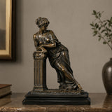 Bronze tabletop sculpture of a neoclassical leaning lady stands on the table indoors.
