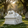 Sleeping lady rests on the white marble tombstone amid sunlit cemetery grass and tombstones.
