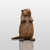 A cute bronze beaver statue stands on the yard surrounded by lush garden plants.