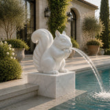 White marble squirrel fountain sits beside swimming pool, water spouts from its mouth.