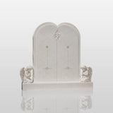 White double marble heart tombstone flanked by two praying angel statues sits in a quiet green memorial garden.