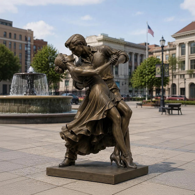 Bronze dancing couple sculpture stands on paved stone plaza beside a city fountain.