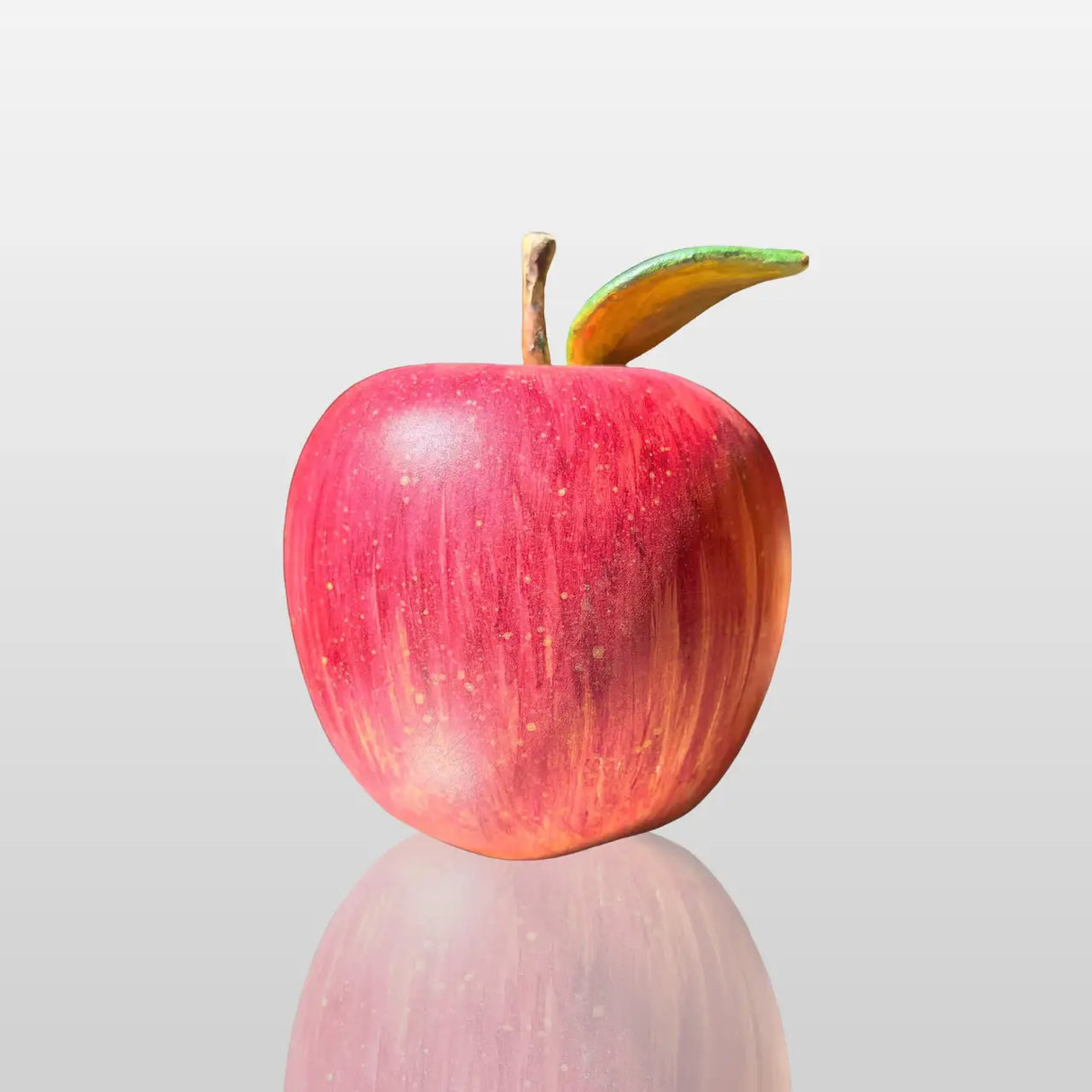 Fiberglass red apple sculpture is displayed on the dark marble table indoors.