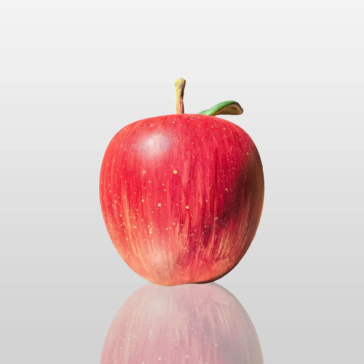 Fiberglass red apple sculpture is displayed on the dark marble table indoors.