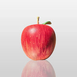 Fiberglass red apple sculpture is displayed on the dark marble table indoors.